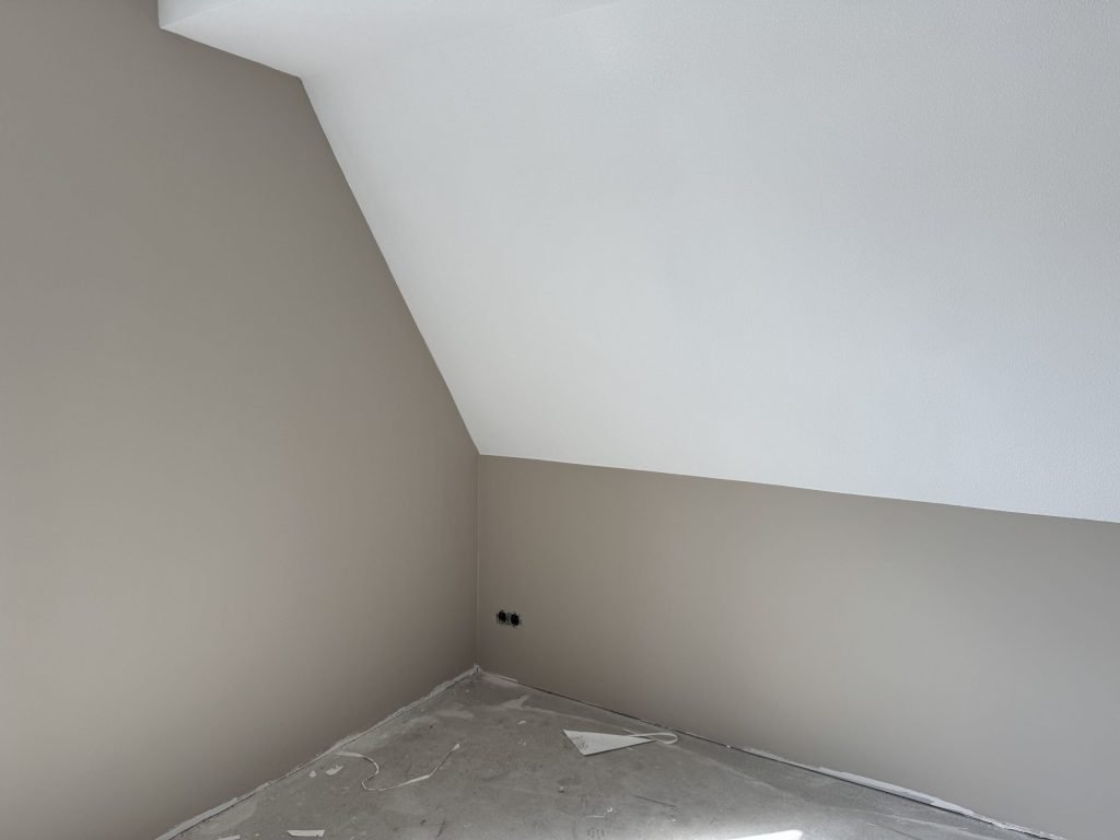 Zolderkamer met een schuine wand, afgewerkt in wit en een warme grijstint